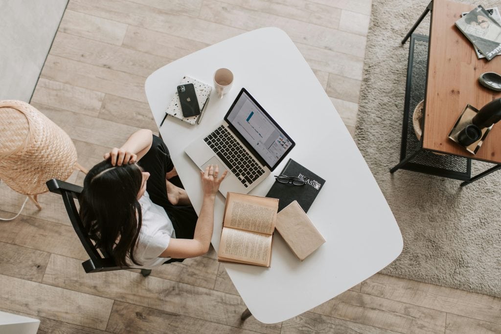 A woman is working on a report on her laptop