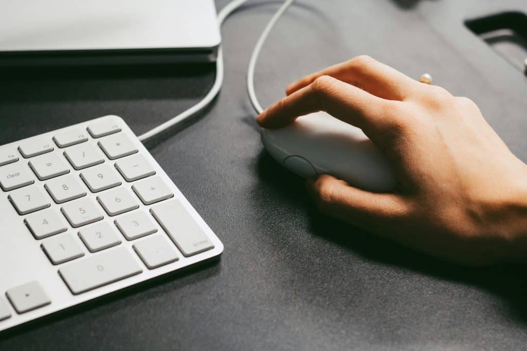 A person's hand holding a computer mouse