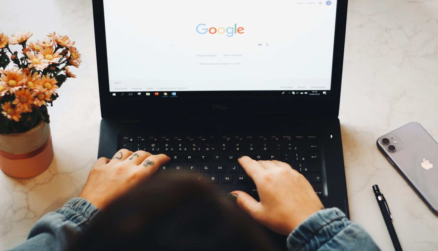 Hands of a person in front of a laptop while doing Google search