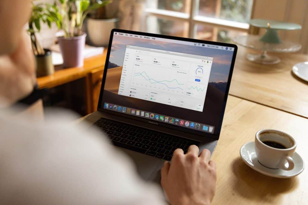 Person viewing analytics dashboard on a laptop at a kitchen table with coffee