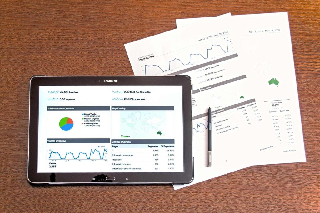 Tablet and printed reports displaying website analytics charts on a wooden desk