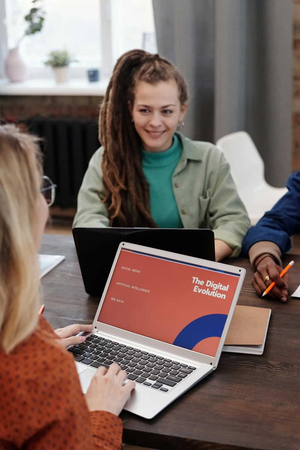 Team meeting with laptops, one screen showing a slide titled “The Digital Evolution.”