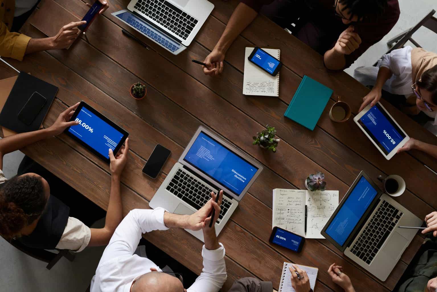 Multiple people in a meeting with laptops and documents on the table