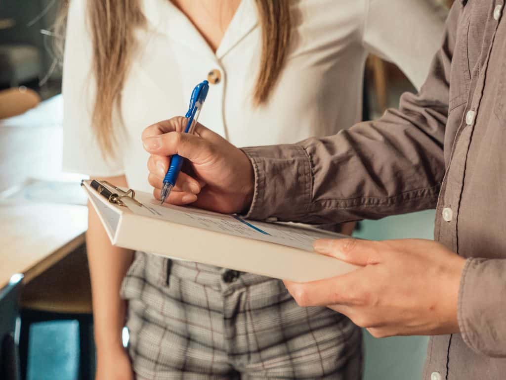Two colleagues discussing while one of them is holding a pen and a document